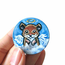 Load image into Gallery viewer, a lightweight wood disc, hand painted with a portrait of a hamster, painted as an angel with wings and a halo, sitting on the clouds against a blue sky. available as a wood keepsake or pendant necklace 
