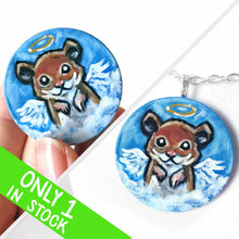 Load image into Gallery viewer, a lightweight wood disc, hand painted with a portrait of a hamster, painted as an angel with wings and a halo, sitting on the clouds against a blue sky. available as a wood keepsake or pendant necklace 
