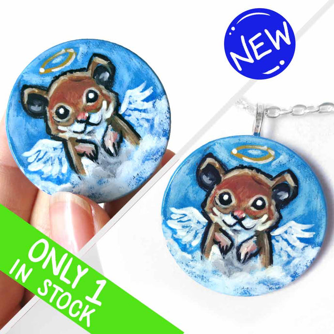 a lightweight wood disc, hand painted with a portrait of a hamster, painted as an angel with wings and a halo, sitting on the clouds against a blue sky. available as a wood keepsake or pendant necklace 