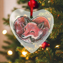 Load image into Gallery viewer, a heart shaped glass ornament, featuring an illustration of a red fox, curled up in the shape of a heart 
