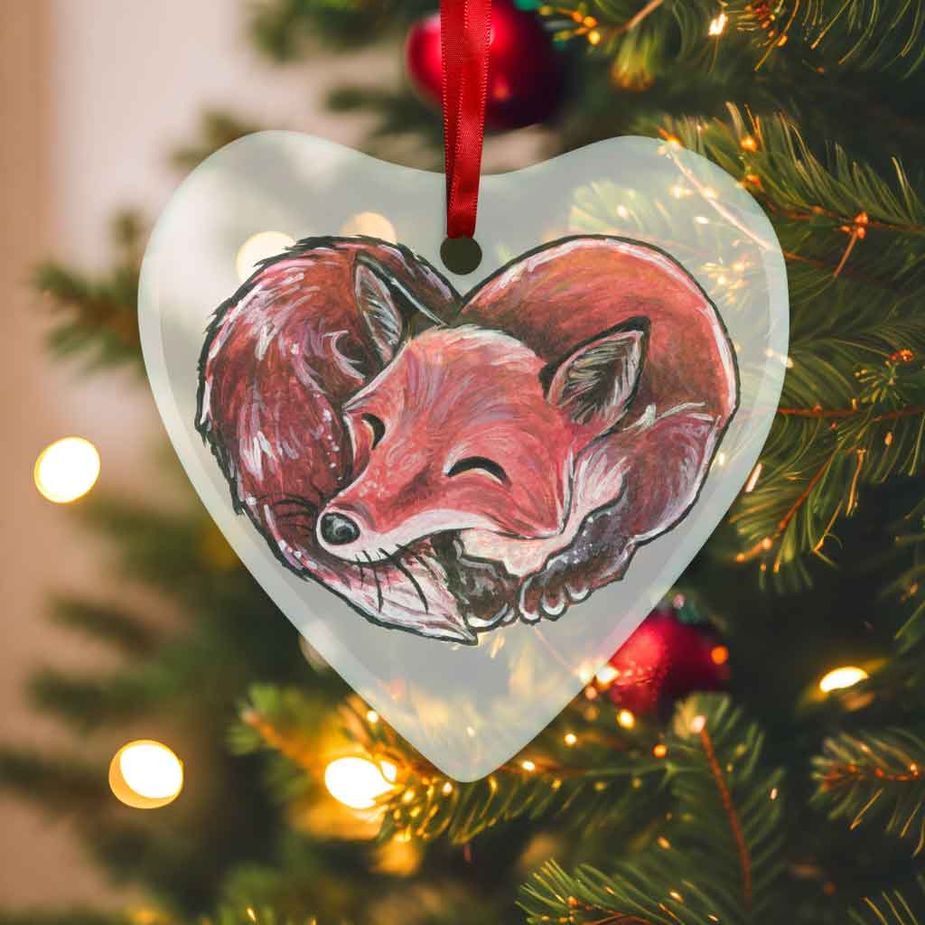 a heart shaped glass ornament, featuring an illustration of a red fox, curled up in the shape of a heart 