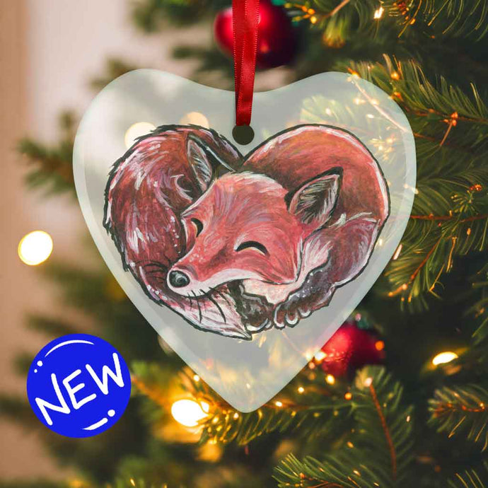 a heart shaped glass ornament, featuring an illustration of a red fox, curled up in the shape of a heart 