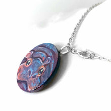 Load image into Gallery viewer, a small smooth wood disc, hand painted with the portrait of a smiling hippopotamus. available as a wood keepsake or pendant necklace 
