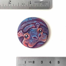 Load image into Gallery viewer, a small smooth wood disc, hand painted with the portrait of a smiling hippopotamus. available as a wood keepsake or pendant necklace 
