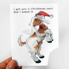 Load image into Gallery viewer, a funny greeting card with a goat on the front, wearing a christmas hat, with the bottom right corner of the card ripped and hanging from its mouth. the card reads, &quot;I got you a Christmas card but  I eated it&quot;
