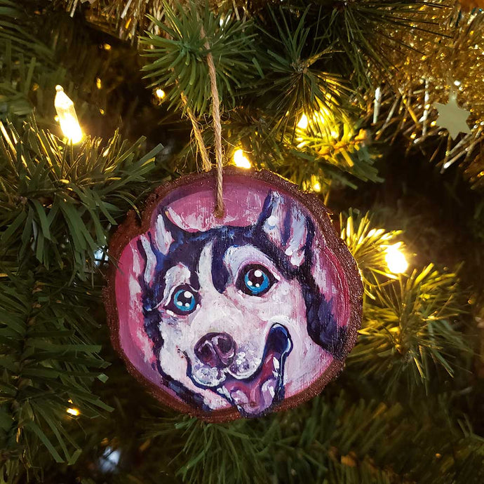 a wood ornament hand painted with a close-up portrait of a husky dog, smiling really big