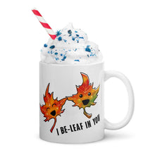 Load image into Gallery viewer, A 11 oz white ceramic mug, printed with art of two maple leaves with happy faces, and the words. &quot;I be-leaf in you&quot;
