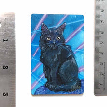 Load image into Gallery viewer, small wood rectangle fridge magnet, hand painted with a portrait of a fluffy black cat with yellow eyes, posing in front of a retro 80s / 90s blue background with blue and pink lasers
