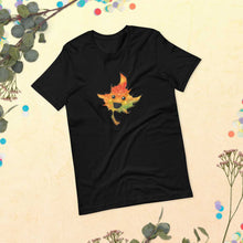 Load image into Gallery viewer, a t-shirt in the colour black, featuring a smiling maple leaf
