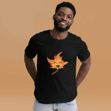Load image into Gallery viewer, a person wears a t-shirt in the colour black, featuring a graphic of a smiling maple leaf
