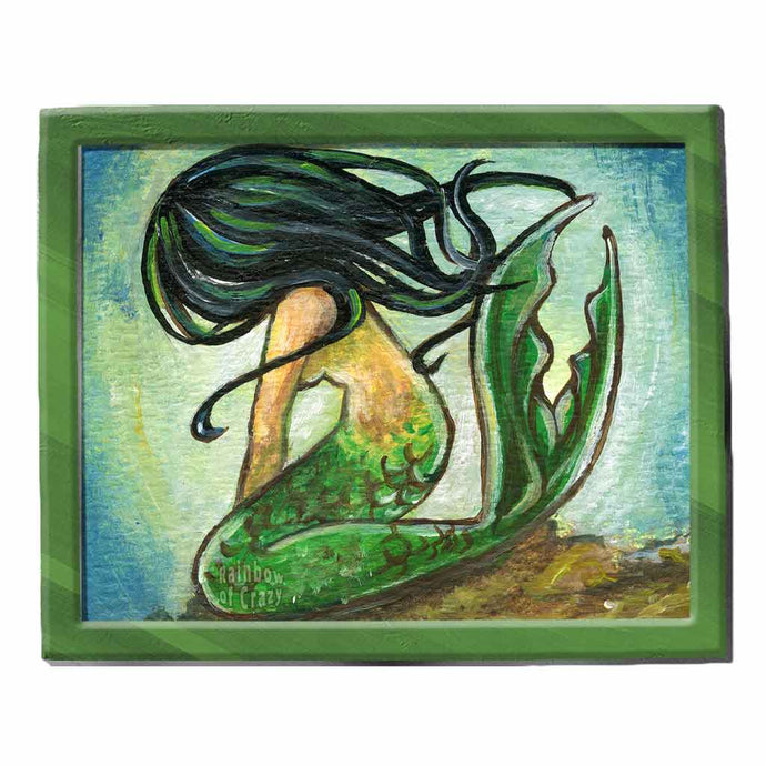 An art print of a mermaid with black hair, sitting down on the ocean floor, face obscured by her hair