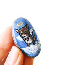 Load image into Gallery viewer, a small beach stone, hand painted with a little brown and white mouse as an angel in the clouds, with a halo and wings. the stone is available as a keepsake rock art or as a pendant necklace
