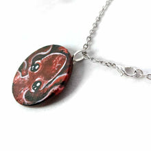 Load image into Gallery viewer, a lightweight wood disc, hand painted with a portrait of a red baby octopus. the painting is available as a keepsake, or pendant necklace
