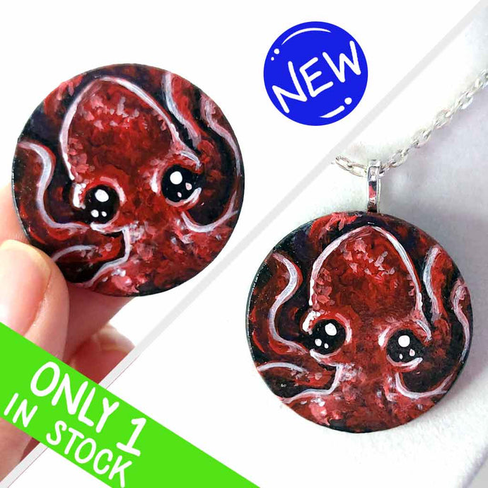 a lightweight wood disc, hand painted with a portrait of a red baby octopus. the painting is available as a keepsake, or pendant necklace
