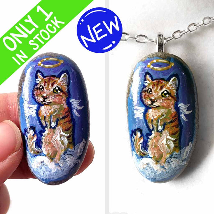 an oval shaped beach stone, hand painted with the portrait of an orange munchkin cat as an angel. standing up on clouds against a royal blue sky. available at a keepsake or pendant necklace