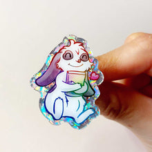 Load image into Gallery viewer, acrylic glitter pin featuring an illustration of a mini lop rabbit hugging a book, with a tiny heart next to him.
