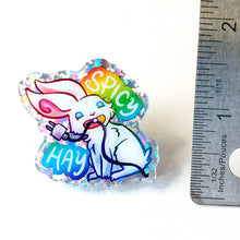 Load image into Gallery viewer, 1.5" sparkly acrylic pin of a smiling white rabbit holding a charging cable in her mouth, with the words "SPICY HAY in rainbow colours.
