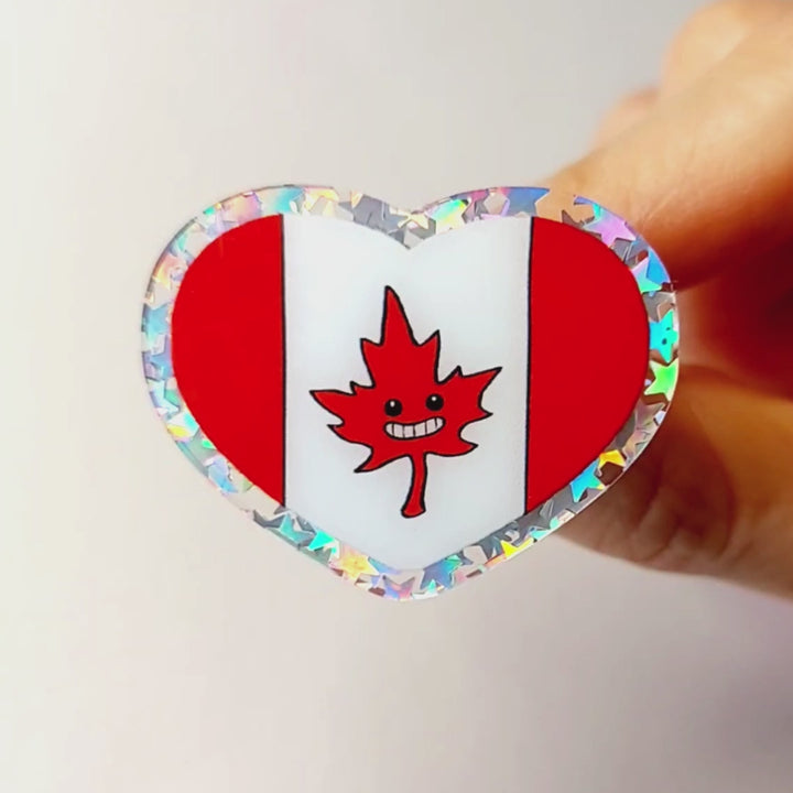 heart acrylic pin featuring the Canada flag, the maple leaf stylized with happy face.