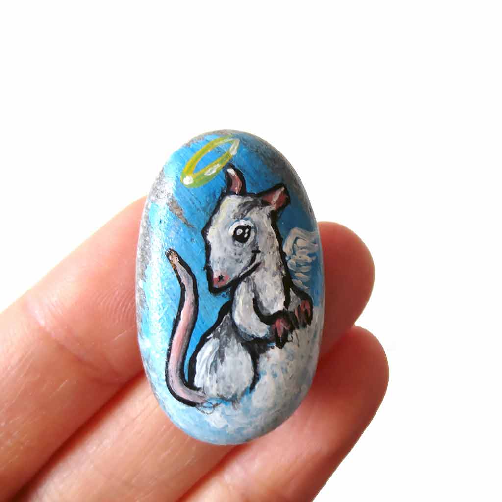 a pet portrait of a white and grey rat as an angel on clouds, painted on a beach rock. available as a beach stone, fridge magnet, or a pendant necklace