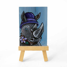 Load image into Gallery viewer, aceo sized painting of a rhino wearing a purple cloche hat and purple flower on a scarf. the painting sits on a small wood easel
