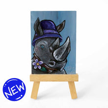Load image into Gallery viewer, aceo sized painting of a rhino wearing a purple cloche hat and purple flower on a scarf. the painting sits on a small wood easel
