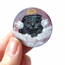 Load image into Gallery viewer, a small wood circle, hand painted with the portrait of a dark gray scottish fold cat, as an angel, with halo and wings, sitting on clouds against a pink and purple sky. available as a wood keepsake or pendant necklace
