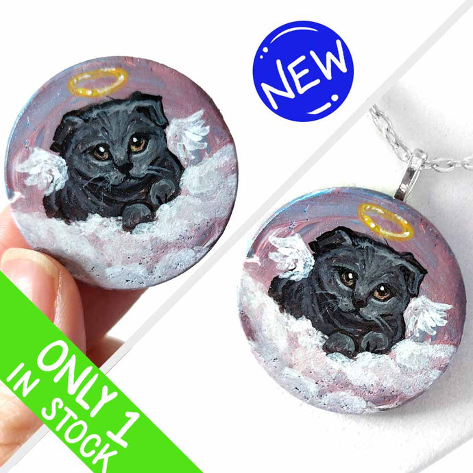 a small wood circle, hand painted with the portrait of a dark gray scottish fold cat, as an angel, with halo and wings, sitting on clouds against a pink and purple sky. available as a wood keepsake or pendant necklace
