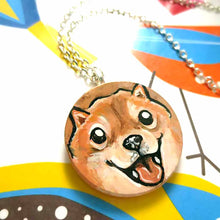 Load image into Gallery viewer, small wood disc painted with a smiling Shiba inu&#39;s face. available as a keepsake or pendant necklace 
