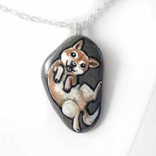 Load image into Gallery viewer, small beach stone, hand painted with a portrait of a shiba inu dog, lying on its back, belly up, tongue blopping out. available as a keepsake rock art or pendant necklace
