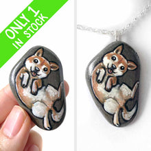 Load image into Gallery viewer, small beach stone, hand painted with a portrait of a shiba inu dog, lying on its back, belly up, tongue blopping out. available as a keepsake rock art or pendant necklace
