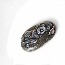 Load image into Gallery viewer, a small beach stone hand painted with the portrait of a silver labrador retriever puppy with blue eyes.
