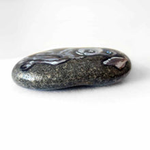 Load image into Gallery viewer, a small beach stone hand painted with the portrait of a silver labrador retriever puppy with blue eyes.
