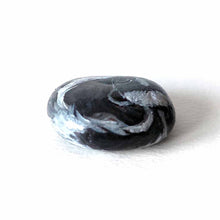 Load image into Gallery viewer, a small beach stone, painted to look like a sleeping baby skunk

