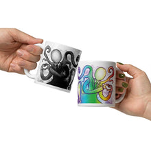 Load image into Gallery viewer, one hand holding a 11 oz white ceramic mug with an illustration of Slender Man forming a heart with his hands. a second hand is holding a second mug, showing it from the other side, featuring the same illustration, mirrored, in all the colours of the rainbow.

