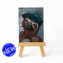 Load image into Gallery viewer, aceo sized painting on a wood easel, features a sloth wearing a navy blue flat cap hat, against a gray background
