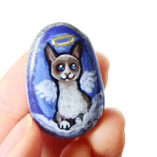 Load image into Gallery viewer, a small beach stone hand painted with the portrait of a snowshoe cat, as an angel on the clouds. available as a keepsake or pendant necklace
