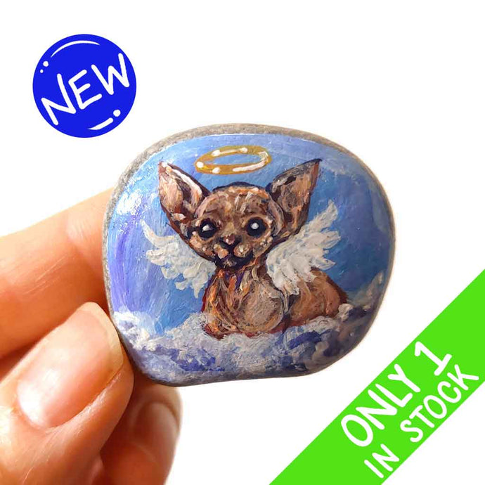 a beach stone, hand painted with a portrait of a sphynx cat, painted as an angel with halo and wings, sitting on fluffy clouds