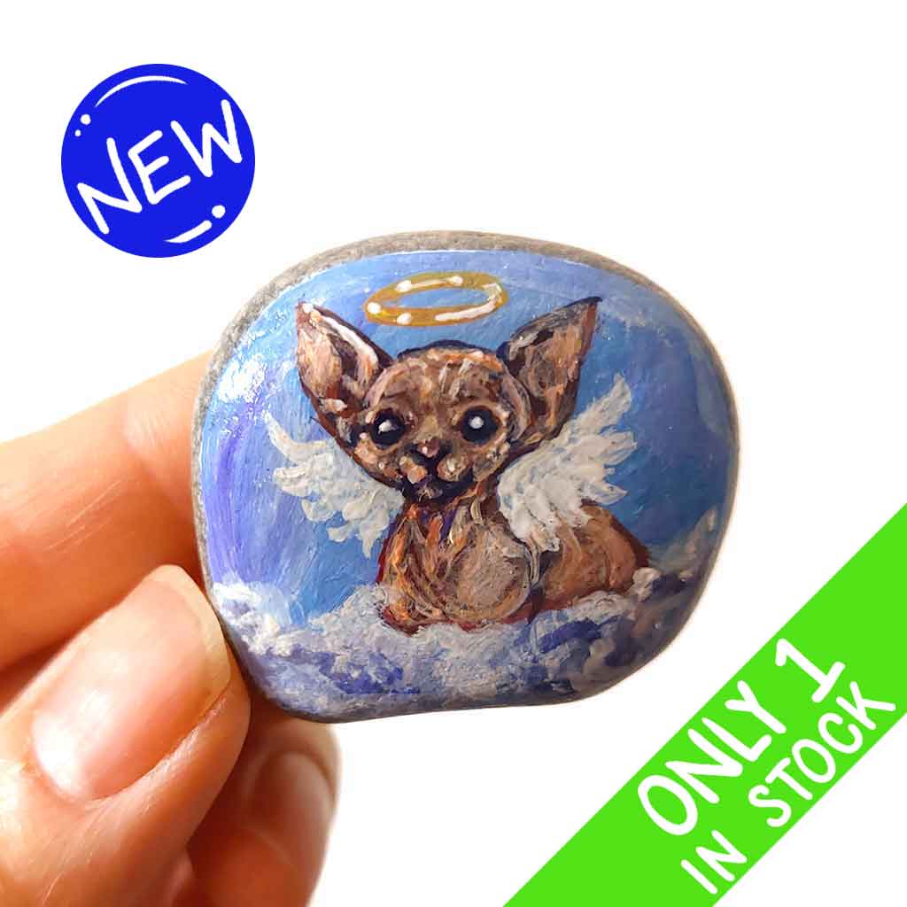 a beach stone, hand painted with a portrait of a sphynx cat, painted as an angel with halo and wings, sitting on fluffy clouds