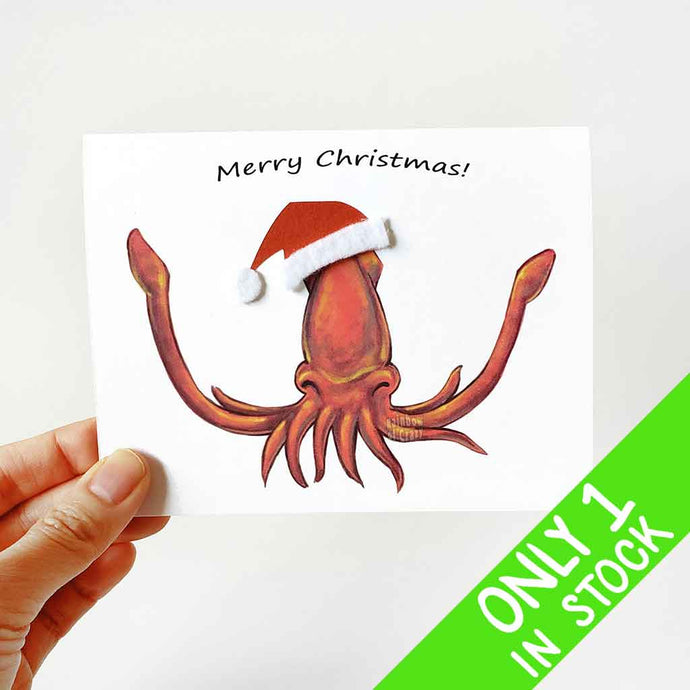 a greeting card with an illustration of a red squid with arms spread wide, wearing a santa hat made with red card stock and whtie felt. the card reads, merry christmas!