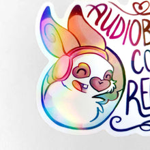 Load image into Gallery viewer, holographic sticker with a smiling rabbit wearing headphones. the sticker reads, "Audiobooks count as reading"
