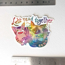 Load image into Gallery viewer, a sticker with a tabby cat next to a ragdoll cat that's holding a book titled "Meow". At the top of the sticker, it says, "Let's read together".
