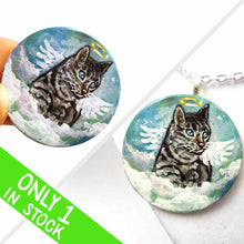 Load image into Gallery viewer, a small wood disc, hand painted with the portrait of a gray tabby cat, as an angel with wings and halo, sitting on clouds against a blue sky. this painting is available as a keepsake or pendant necklace
