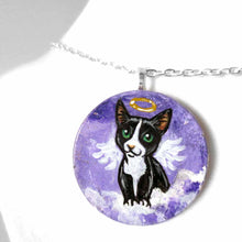 Load image into Gallery viewer, a portrait of a tuxedo cat as an angel, sitting on clouds against a purple sky, painted on a small wood disc, available as a keepsake or pendant necklace
