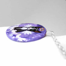 Load image into Gallery viewer, a portrait of a tuxedo cat as an angel, sitting on clouds against a purple sky, painted on a small wood disc, available as a keepsake or pendant necklace
