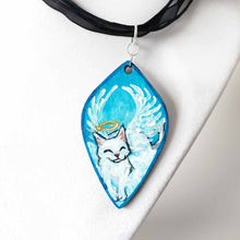 Load image into Gallery viewer, diamond shaped wood pendant necklace, hand painted with a smiling white cat as an angel, eyes closed, with a halo and wings, lying on clouds against a blue sky
