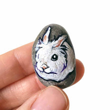 Load image into Gallery viewer, a small beach stone, hand painted with a portrait of a white lionhead rabbit. available as a keepsake or pendant necklace
