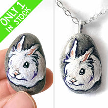 Load image into Gallery viewer, a small beach stone, hand painted with a portrait of a white lionhead rabbit. available as a keepsake or pendant necklace
