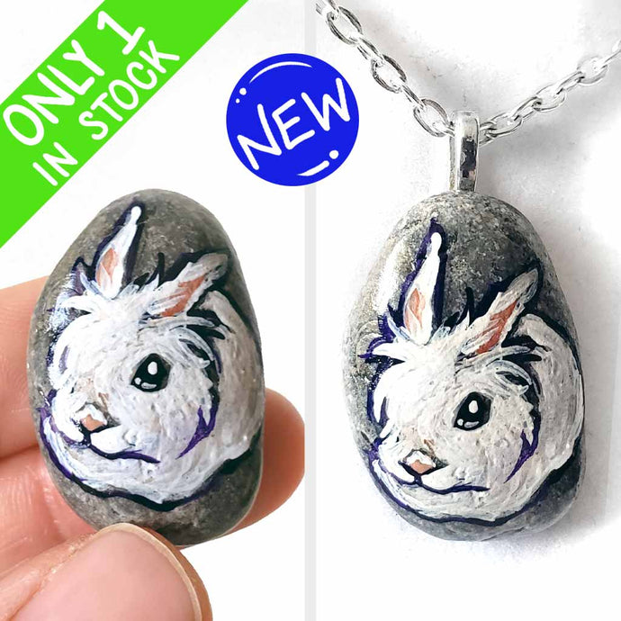 a small beach stone, hand painted with a portrait of a white lionhead rabbit. available as a keepsake or pendant necklace