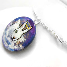 Load image into Gallery viewer, a wood disc, hand painted with the portrait of a white rabbit with blue eyes, painted as an angel, with halo and wings, sitting on clouds against a blue sky. available as a keepsake or pendant necklace
