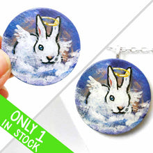 Load image into Gallery viewer, a wood disc, hand painted with the portrait of a white rabbit with blue eyes, painted as an angel, with halo and wings, sitting on clouds against a blue sky. available as a keepsake or pendant necklace
